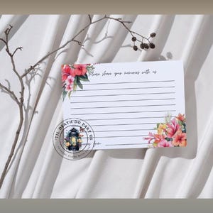 Op de afbeelding: Een witte kaart met gelijnde ruimtes om op te schrijven, versierd met bloemmotieven in roze, rood en geel. De tekst "Please share your memories with us" staat bovenaan. Een cirkelvormig logo met een lantaarn staat onderaan.