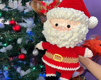 May include: A handmade crochet Santa Claus doll. The doll features a red suit, a white beard and hat trim, and a black belt with a gold buckle. The doll is approximately 12 inches tall and is a festive holiday decoration.