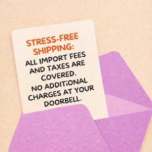 May include: A white card with orange text that reads "STRESS-FREE SHIPPING: ALL IMPORT FEES AND TAXES ARE COVERED. NO ADDITIONAL CHARGES AT YOUR DOORBELL." is partially inserted into a light purple envelope.