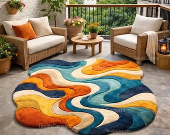May include: A colorful, wavy area rug with a retro design. The rug features shades of orange, yellow, blue, and cream. The rug is placed on a patio with wicker furniture and potted plants, creating a cozy outdoor living space.