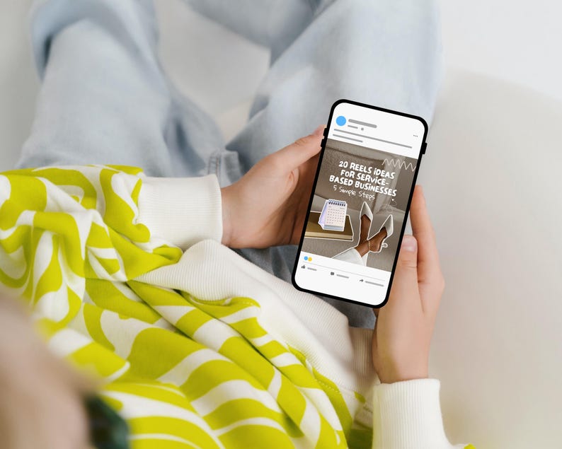 May include: A person holding a smartphone displaying a social media post. The post reads "20 Reels Ideas for Service-Based Businesses." The person wears a white and yellow patterned sweater. The phone screen shows a calendar and white heels.