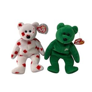 May include: Two plush toy bears. One is white with red maple leaf patterns, the other is solid green with a shamrock. Both have black eyes and noses, and hang tags.
