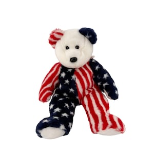 May include: A plush teddy bear with a patriotic design. The bear's body is split, with one side featuring red and white stripes and the other side displaying a blue field with white stars. The head is white, and the ears are red and blue.