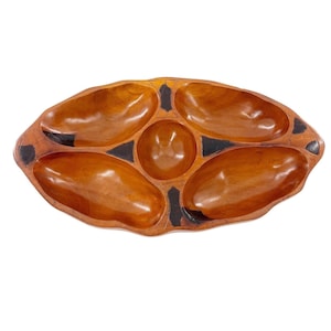 Könnte beinhalten: Ein hölzernes Serviertablett mit fünf Fächern. Das Tablett ist oval geformt und hat eine natürliche Holzoberfläche und schwarze Akzente. Die Fächer sind in verschiedenen Größen und Formen, ideal zum Servieren von Snacks oder Vorspeisen.