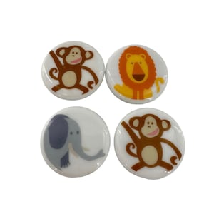 May include: Four round, white buttons with cartoon animal designs. Two buttons feature monkeys, one with a lion, and one with an elephant. The animals are in shades of brown, orange, and gray.