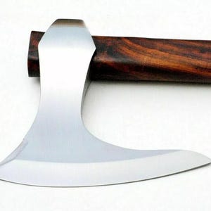 以下が含まれることがあります： 湾曲した刃を持つ、研磨されたスチール製の斧頭のクローズアップ。 斧頭は濃い茶色の木製の柄に取り付けられています。 柄には豊かな天然の木目模様があります。 斧は白い背景に配置されています。