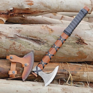 May include: A handcrafted axe with a wooden handle wrapped in black leather. The axe head is silver with a curved blade. A brown leather sheath is included. The axe is approximately 18 inches long.