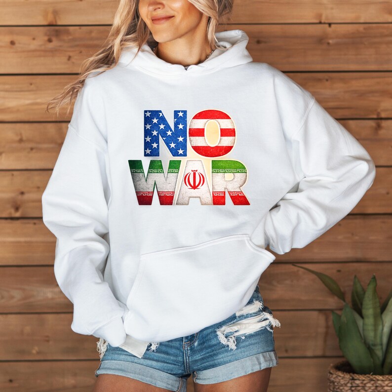May include: White hoodie with the words "NO WAR" in a patriotic design. The "NO" is in the colors of the American flag, and the "WAR" is in the colors of the Iranian flag. The hoodie has a front pocket and a drawstring hood.