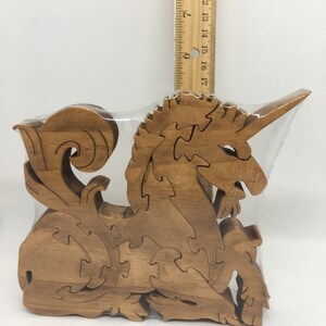 May include: A wooden jigsaw puzzle of a unicorn, with intricate details and a brown stain finish. The puzzle is packaged in a clear plastic bag.