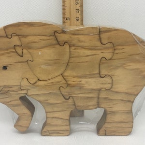 May include: A wooden elephant puzzle with five pieces. The puzzle is made of light brown wood with a natural grain pattern.