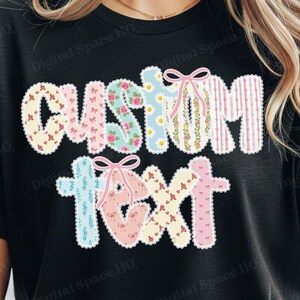 May include: Black t-shirt with the words "CUSTOM TEXT" in a colorful, patchwork design. The letters are decorated with floral patterns, stripes, and bows, creating a cheerful and personalized look.