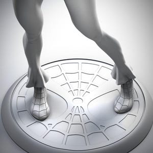 Puede incluir: Una escultura gris tridimensional de un superh&eacute;roe, posando sobre una base redonda con un dise&ntilde;o de telara&ntilde;a. La figura est&aacute; en una postura din&aacute;mica, con un brazo levantado y las piernas separadas. La escultura es detallada y parece estar hecha de un material liso.