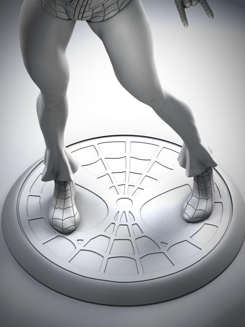 Puede incluir: Una escultura gris tridimensional de un superh&eacute;roe, posando sobre una base redonda con un dise&ntilde;o de telara&ntilde;a. La figura est&aacute; en una postura din&aacute;mica, con un brazo levantado y las piernas separadas. La escultura es detallada y parece estar hecha de un material liso.