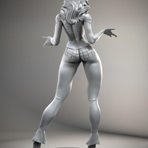 Puede incluir: Figura gris de un personaje femenino, vista desde atr&aacute;s, con pelo largo y ondulado. La figura lleva una parte inferior con dise&ntilde;o de telara&ntilde;a y botas. La figura est&aacute; sobre una base redonda con un dise&ntilde;o de telara&ntilde;a.