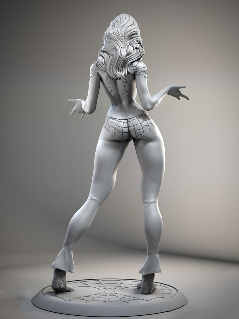 Puede incluir: Figura gris de un personaje femenino, vista desde atr&aacute;s, con pelo largo y ondulado. La figura lleva una parte inferior con dise&ntilde;o de telara&ntilde;a y botas. La figura est&aacute; sobre una base redonda con un dise&ntilde;o de telara&ntilde;a.
