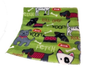May include: Green fleece fabric with a repeating pattern of dogs in various poses and colors. The fabric has the words "Fetch", "Woof!" and "Roll Over" printed on it.