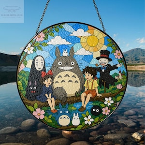 May include: Round stained glass window featuring characters from the animated film "My Neighbor Totoro." The design includes Totoro, other characters, and a sunny sky. The window is framed in black and hangs from a chain.