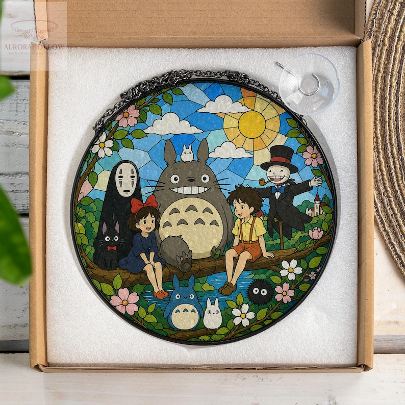 May include: Round stained glass panel featuring a colorful illustration of characters from the animated film "My Neighbor Totoro." The artwork depicts Totoro, Mei, Satsuki, and other characters in a vibrant outdoor scene with a blue sky and yellow sun.