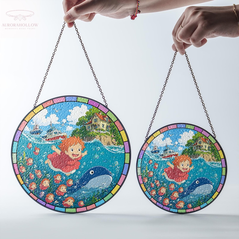 May include: Two round stained glass panels with a chain for hanging. Each panel features a colorful illustration of a girl, a whale, and a coastal scene. The panels have a rainbow-colored border and are held up by hands.
