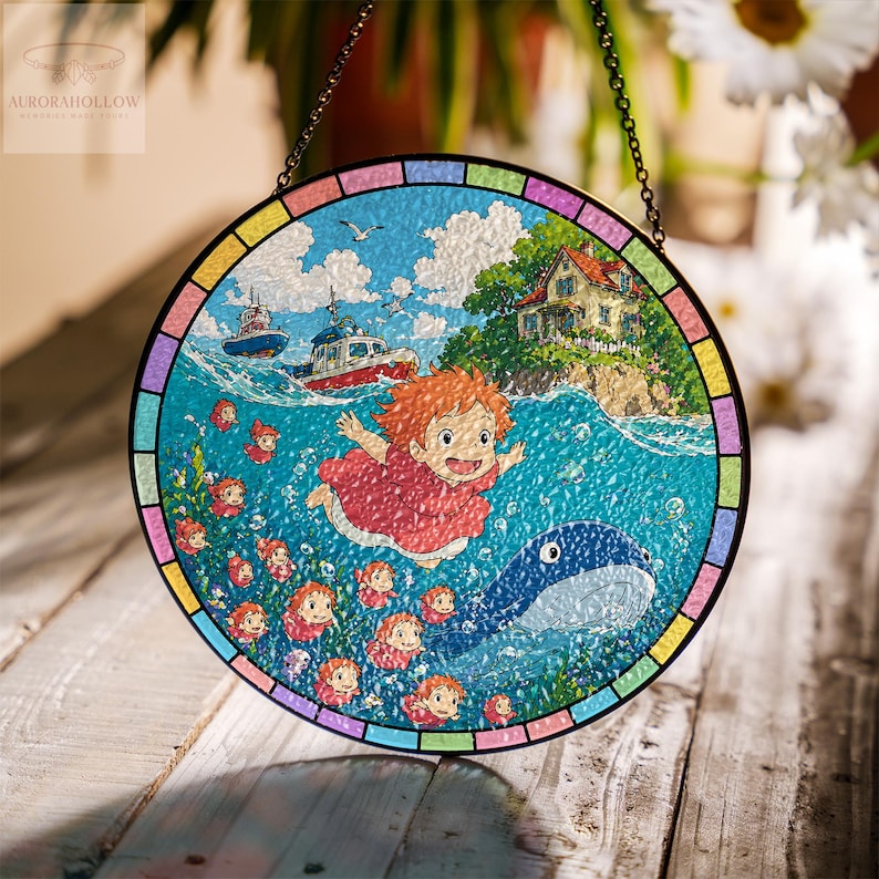 May include: Round stained glass window featuring a vibrant illustration of a girl with red hair, a whale, and boats on a blue ocean. The artwork includes a house on an island, seagulls, and a colorful border. A chain is attached for hanging.