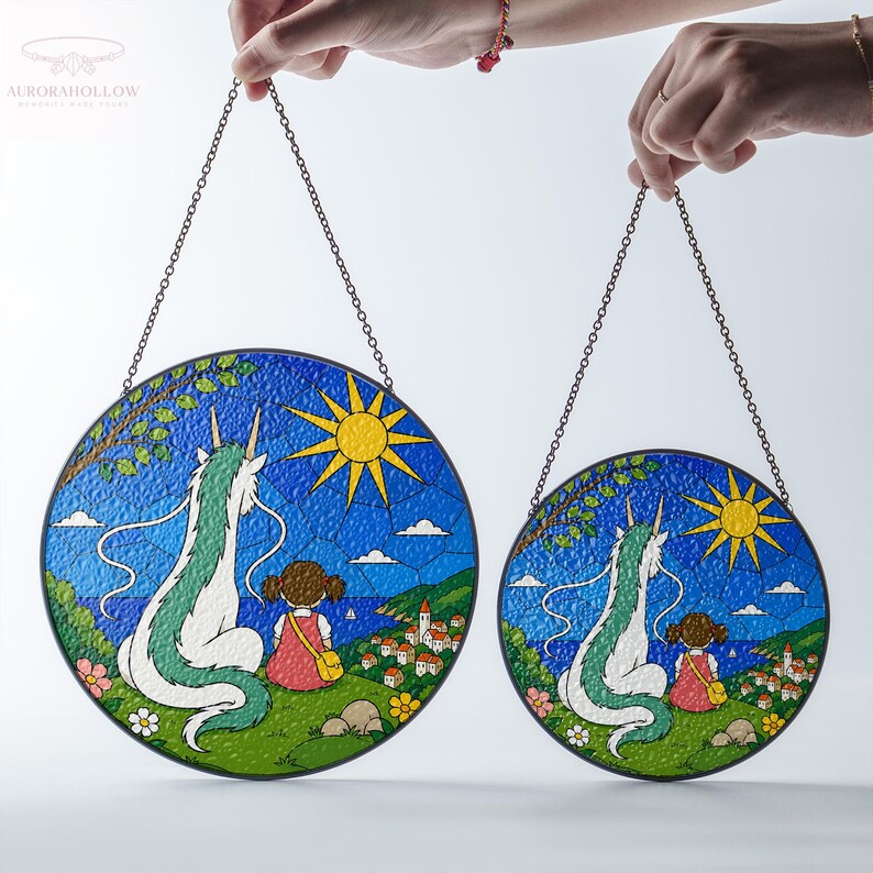 May include: Two round stained glass panels with chain hangers. Each features a dragon, a girl, and a sun against a blue sky and landscape. The dragon is white and green, the girl wears a pink dress, and the sun is yellow.