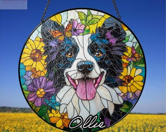 May include: Round stained glass window featuring a black and white dog with a pink tongue, surrounded by colorful flowers and butterflies. The dog's name, "Ollie," is written in cursive. A chain is attached for hanging.