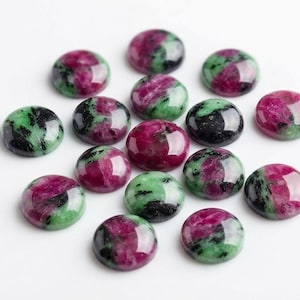 Puede incluir: Un conjunto de quince cabujones redondos y pulidos con un patrón moteado de magenta vibrante, verde bosque profundo e inclusiones negras. Cada piedra tiene una superficie lisa y abovedada con un acabado brillante, dispuestas en grupo.