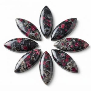 May include: Seven marquise-shaped cabochons arranged in a circular pattern. Each stone features a polished surface with a mottled texture, displaying a mix of deep black, dark grey, and vibrant magenta-red inclusions throughout the material.