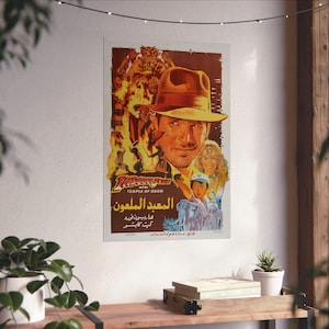 May include: A vintage movie poster for "Indiana Jones and the Temple of Doom." The poster features a portrait of the main character wearing a fedora, with flames and other characters in the background. The title is in English and Arabic.