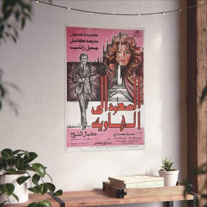 May include: A vintage movie poster with Arabic text and illustrations. The poster features a man in a suit and a woman with curly hair, with the Eiffel Tower in the background. The colour scheme is primarily pink, red, and black.