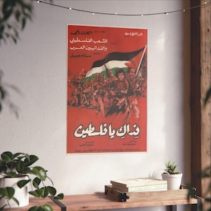 May include: A vintage poster with Arabic text and a red background. The poster features illustrations of people carrying weapons and a Palestinian flag. The text includes the words "Palestine" and "The Palestinian People". The poster is displayed on a white wall.