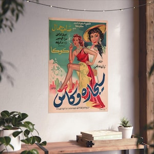 May include: Vintage movie poster featuring two women. One woman is in a red dress, smoking a cigarette, and the other is wearing a hat. The poster has Arabic text and a retro design with a green and blue color scheme.