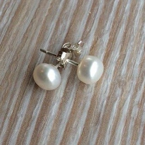 May include: A pair of white pearl stud earrings with silver posts.