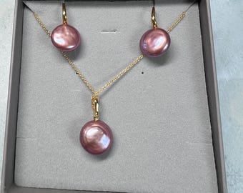 Könnte beinhalten: Ein Perlenschmuck-Set mit einer Halskette und Ohrringen. Die Perlen sind in einem zarten Rosaton gehalten und in Gold gefasst.