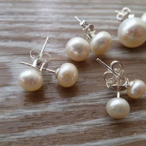 Picture shows 4 pairs of circular, white coloured pearl stud earrings, with silver post and scroll back/butterfly fixings. Earrings are of varying sizes.