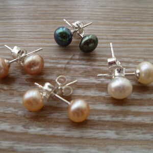 Picture shows 4 pairs of circular pearl stud earrings, with silver post and scroll back/butterfly fixings. Colours shown are white, peach, peacock blue and pink.