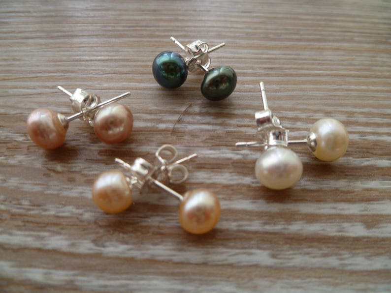 Picture shows 4 pairs of circular pearl stud earrings, with silver post and scroll back/butterfly fixings. Colours shown are white, peach, peacock blue and pink.