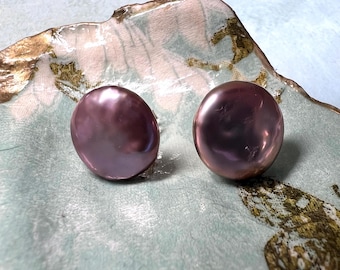 Könnte beinhalten: Ein Paar runde, irisierende, violette Perlenohrringe. Die Perlen sind glatt und haben eine leicht unregelmäßige Form.