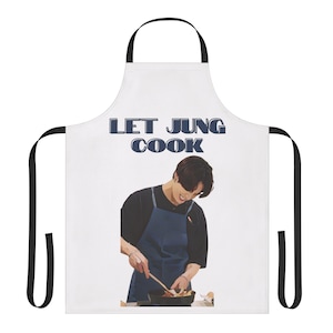 May include: White apron with black straps featuring the text "LET JUNG COOK" in blue letters. The apron has an illustration of a person wearing a blue apron and cooking. The person is smiling and holding a wooden spoon.
