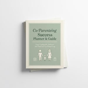以下が含まれることがあります： 「Co-Parenting Success Planner & Guide」というタイトルのプランナーとガイド。薄い緑色の表紙に白い文字が書かれています。表紙には家族のイラストとアイコンが含まれています。プランナーはメモ帳の上にあります。