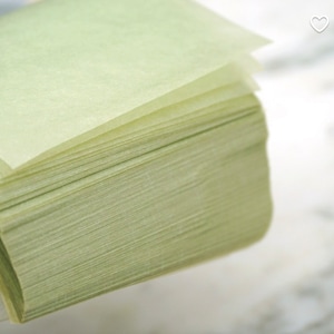 May include: A stack of light green, thin, rectangular sheets of paper.
