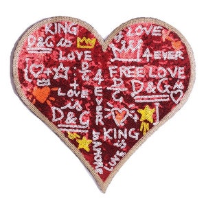 May include: Red heart-shaped patch with a gold outline, covered in sequins and decorated with white graffiti-style lettering that says "KING", "D&G", "LOVE", "4EVER", "FREE LOVE", and "D&G".