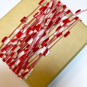 May include: Red and white fuzzy ribbon on a gold gift box.