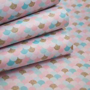 May include: Pink, blue, and gold mermaid scale fabric with a glitter finish. The fabric is folded in a stack of four layers.
