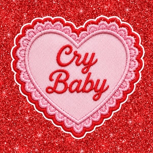 May include: A heart-shaped embroidered patch featuring a light pink center with the red text Cry Baby in a cursive font. The patch has a scalloped border with alternating layers of light pink and red thread, set against a bright red glitter background.