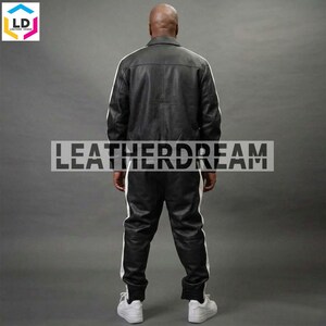 May include: A black leather jacket and matching black leather trousers set featuring white vertical stripes running down the sleeves and the sides of the legs. The back of the jacket and trousers are visible, with the text LEATHERDREAM overlaid.