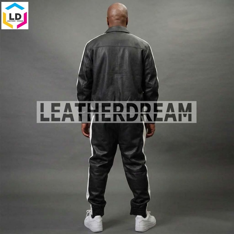May include: A black leather jacket and matching black leather trousers set featuring white vertical stripes running down the sleeves and the sides of the legs. The back of the jacket and trousers are visible, with the text LEATHERDREAM overlaid.