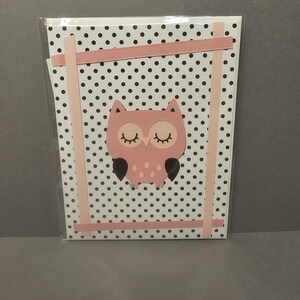 May include: A pink owl card with a black and white polka dot background. The owl has closed eyes and black accents. The card is framed with pink strips and is in a clear plastic sleeve.