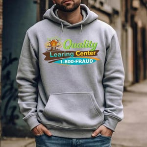 Puede incluir: Una sudadera con capucha gris con un bolsillo delantero. La sudadera presenta un gráfico colorido con las palabras "Quality Learing Center" y el número de teléfono "1-800-FRAUD". El gráfico incluye un diseño de casa en el árbol.