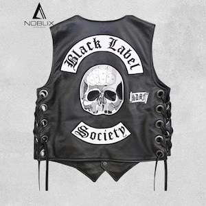 Op de afbeelding: Zwart leren vest met een schedelafbeelding en de woorden "Black Label Society" en "Society" in witte letters. Het vest heeft veters aan de zijkanten en een knoopsluiting. De merknaam "Noblix" staat linksboven.